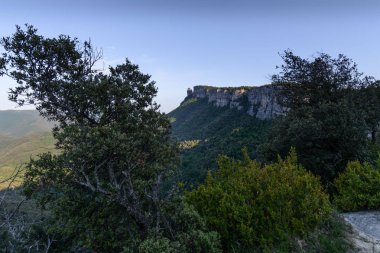 Bazı ağaçların altında bir mavi gökyüzü ve yeşillik Katalonya, İspanya ile görülen bir uzak uçurum yaz bahar sahnesi
