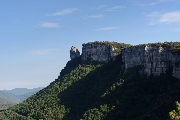 Impressive cliff projects its shadow in a warm sunny day over the closest forest of Sallent in catalonia, Spain