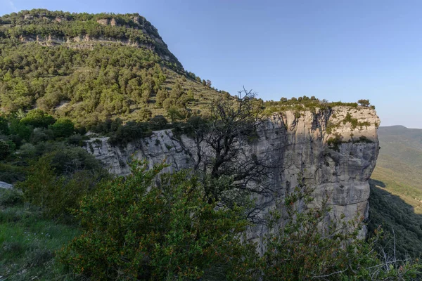 Tehlikeli yüksek dik kayalık yüz küçük tepenin altında Catalonia, İspanya yakın bir bakış açısı alınan bir mavi gökyüzü gün arıyorum