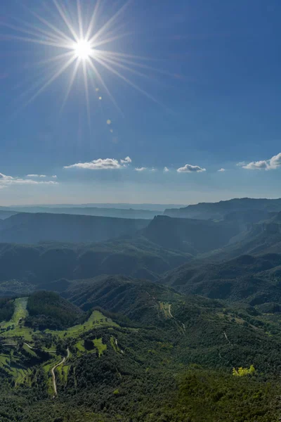 Bright sun projecting its rays over the green forest of various mountains in a sunny summer day at Catalonia, Spain