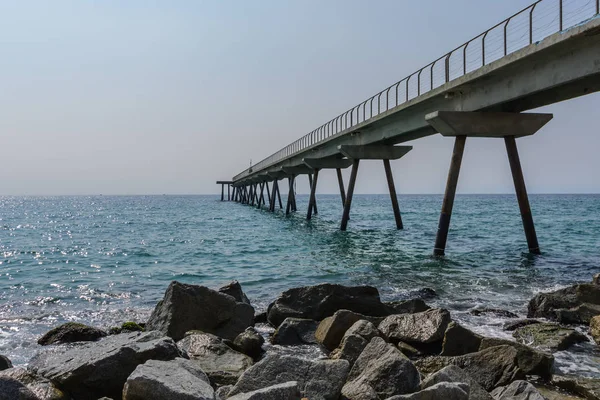 Büyük kayalara bir sürü büyük bir köprü bir güneşli yaz günde Badalona, İspanya lay