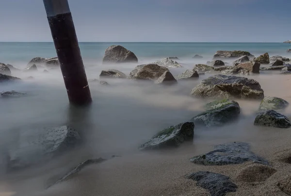 Uzun pozlama birkaç taş ve bir ayağı için sis İspanyol kıyıları Barselona, banyo Akdeniz suları dönüştürmek gibi görünüyor