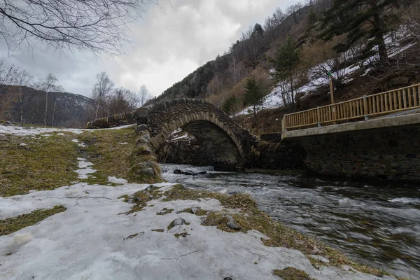 Bir taş köprü bir nehir ve yakın bazı kar Andorra'da yukarıda bir soğuk kış sahne
