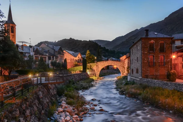 Bir köyün ışıkları nehir ve binalar çok çeşitli renklere Esterri d'Aneu, İspanya ile güzel bir manzara akşam zamanında aydınlatmak