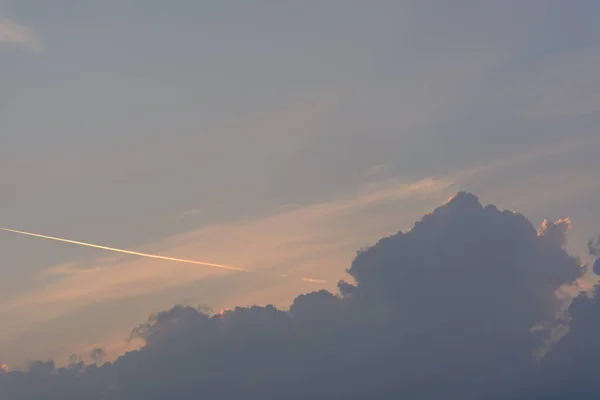 Koyu mavi ve turuncu bulutlar nedeniyle uçak iz ile gelen günbatımı