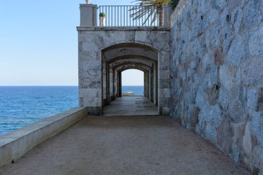 Açık bir günde Platja d'Aro, İspanya, Akdeniz'de deniz tarağı sularına yakın bir balkon altında kemerli bir geçit