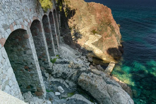 Büyük kemer stand bir merdiven kurmak yanında Akdeniz'ın suları Platja d'Aro, İspanya, doğru bir kaya üzerinde içeren bir bina