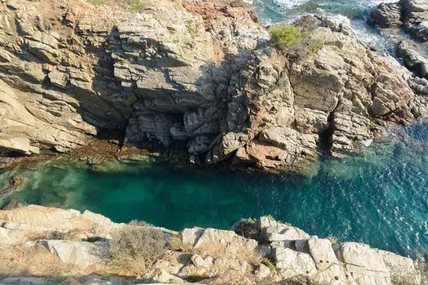 Küçük bir çalı Platja d'Aro, İspanya Akdeniz yanındaki bir derin zümrüt rengi akışında benzeyen riskleri arasında bir geçiş