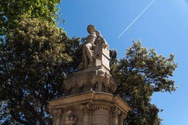 Ağaçların önündeki heykel ve bir uçağın izi