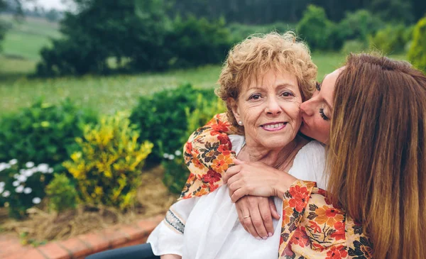 Mulher sênior em uma cadeira de rodas com sua filha — Fotografia de Stock