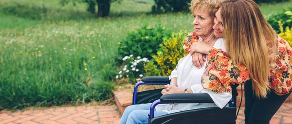 Mulher sênior em uma cadeira de rodas com sua filha — Fotografia de Stock