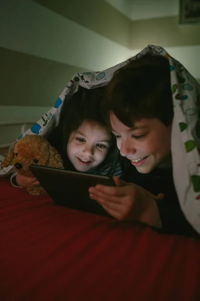 Brothers looking at the tablet in the dark — Stock Photo, Image