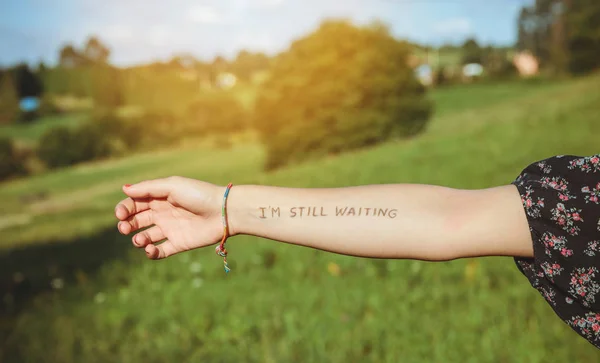 Brazo femenino con texto - Sigo esperando - escrito en piel — Foto de Stock