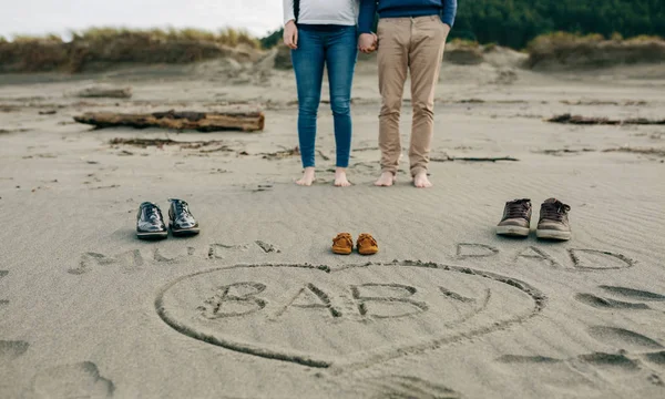 Mamãe, papai e bebê escrito na areia com os pais por trás — Fotografia de Stock