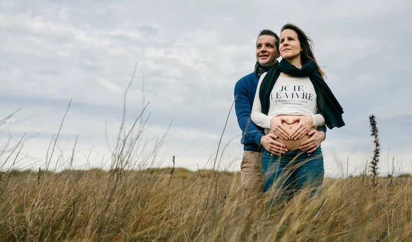 Schwangere macht Herz mit Händen auf nacktem Bauch mit Partner — Stockfoto