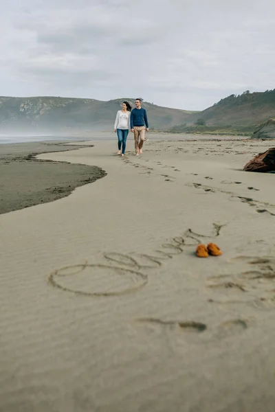 Eltern gehen mit Baby-Namen Oliv in den Sand geschrieben — Stockfoto