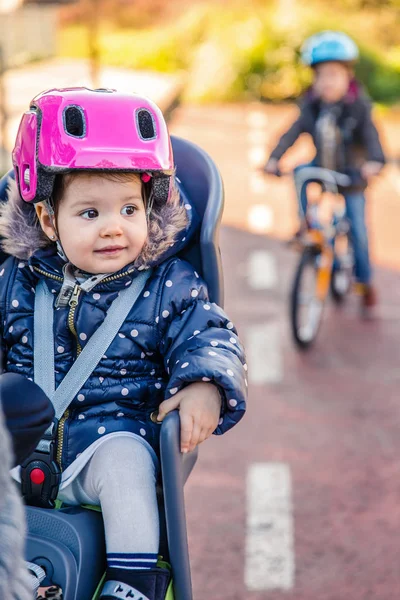 Lttle fille avec casque sur la tête assis dans le siège de vélo — Photo