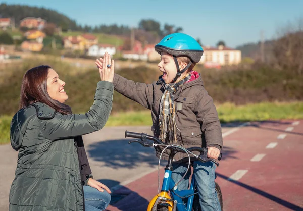 Mãe e filho dando cinco por sucesso andar de bicicleta — Fotografia de Stock