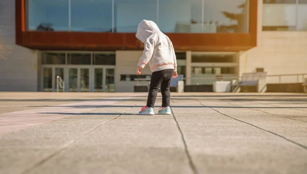 Dziewczynka z kapturem patrząc jej trampki na zewnątrz — Zdjęcie stockowe