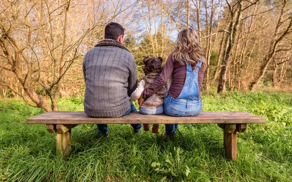 Mann und Frau umarmen kleines Mädchen auf einer Bank — Stockfoto