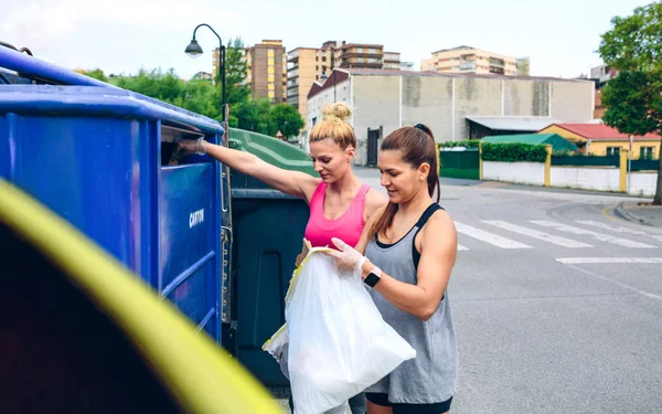 Chicas arrojando basura al contenedor de reciclaje — Foto de Stock