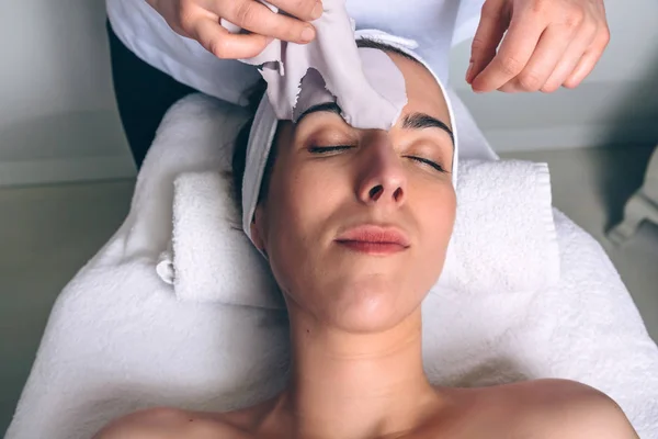 Kvinna och avlägsnar facial mask behandling i spa — Stockfoto