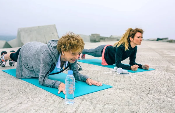 Mujer mayor y entrenador haciendo ejercicio de tablón —  Fotos de Stock