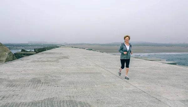 Senior sportswoman with headphones running — Stock Photo, Image