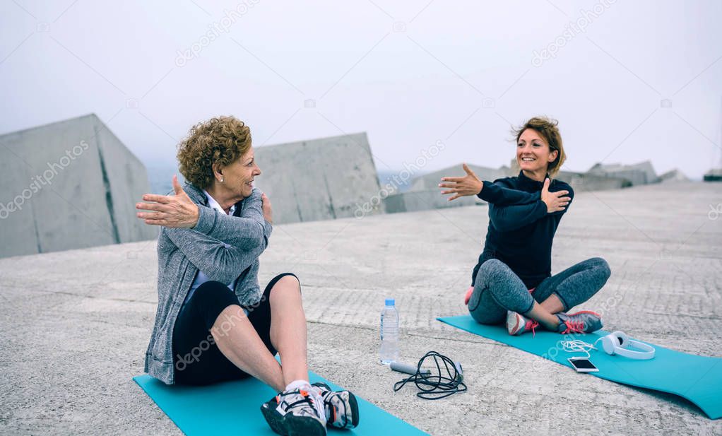 Senior woman stretching with female coach