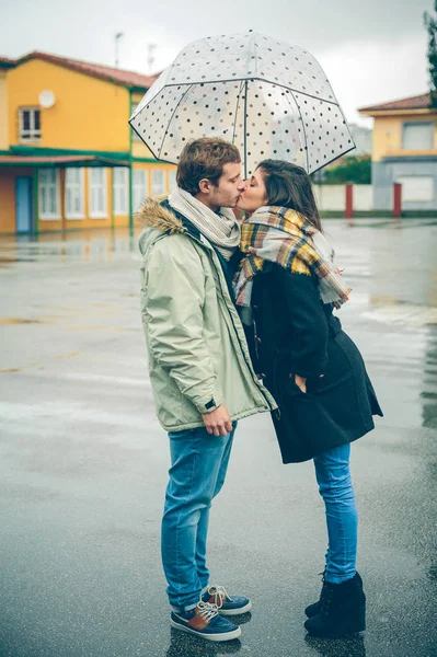 Jong koppel zoenen buitenshuis onder paraplu op een regenachtige dag — Stockfoto