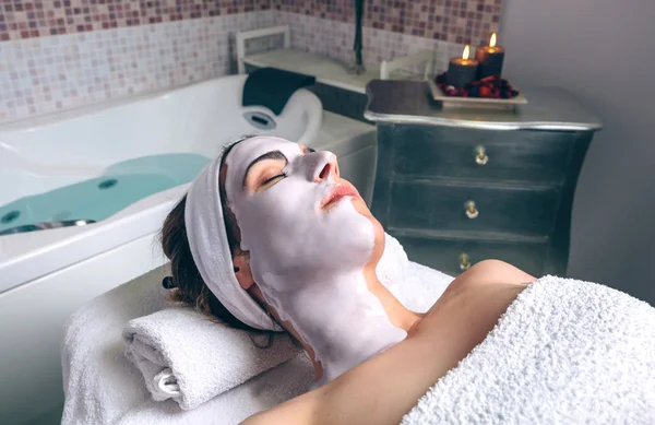 Relaxed woman lying with facial mask in spa — Stock Photo, Image