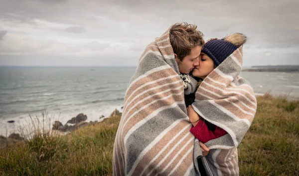 Молода пара цілується на відкритому повітрі під ковдрою в холодний день — стокове фото