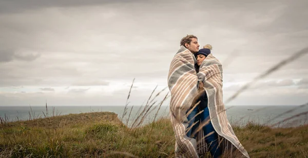 Young couple embracing outdoors under blanket in a cold day — Stock Photo, Image