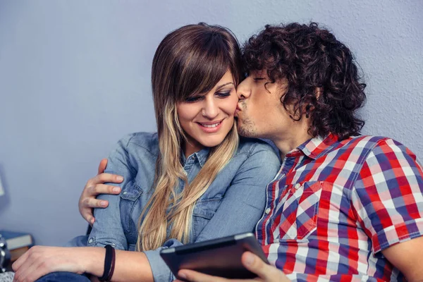 Мужчина целует молодую женщину и держит планшет — стоковое фото