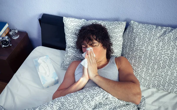 Sick man sneezing and covering nose with tissue — Stock Photo, Image