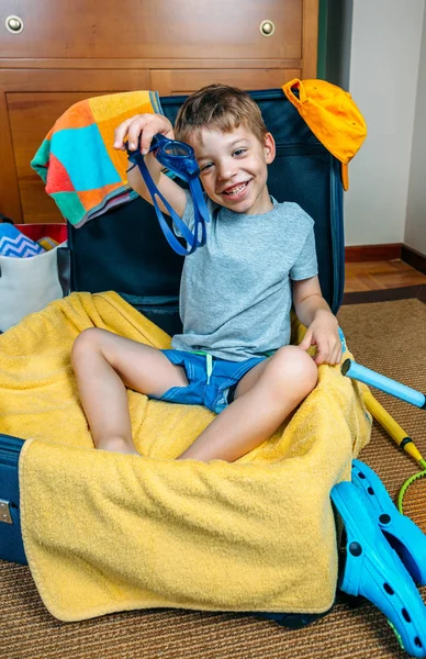 Niño feliz sonriendo sentado dentro de una maleta — Foto de Stock