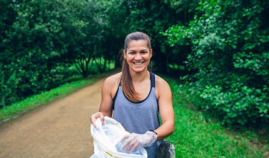 Kız açık havada plogging yapıyor plastik torba ile poz gülümseyen