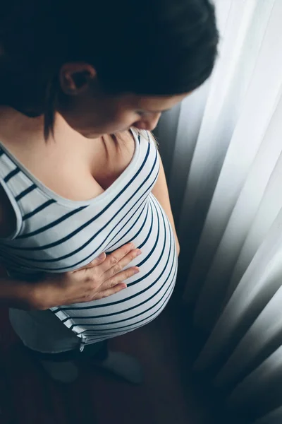 Zwangere vrouw op zoek naar haar buik — Stockfoto