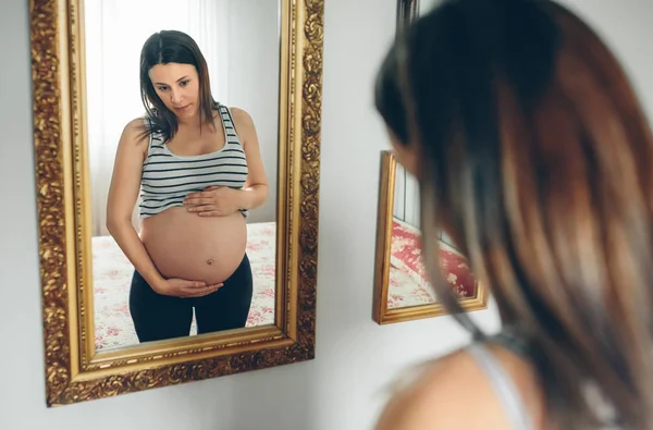 Těhotná žena hledá její břicho — Stock fotografie