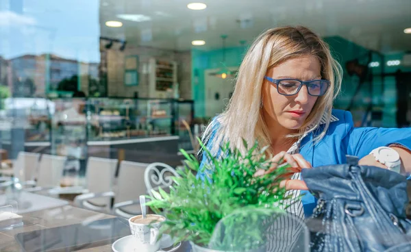 Arbeitende Frau schaut in ihre Handtasche — Stockfoto