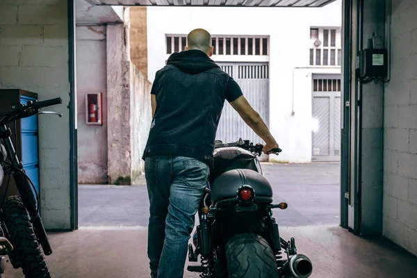 Człowiek z niestandardowych motocykl opuszczeniu garażu — Zdjęcie stockowe