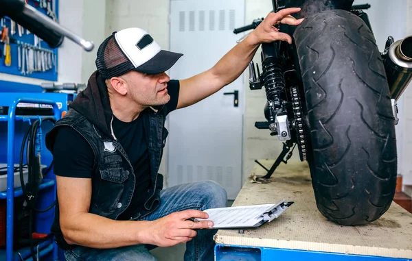 Mechanic checking wheel of a customized motorcycle — Stock Photo, Image