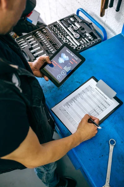 Mecânico usando aplicativo tablet e tomar notas — Fotografia de Stock