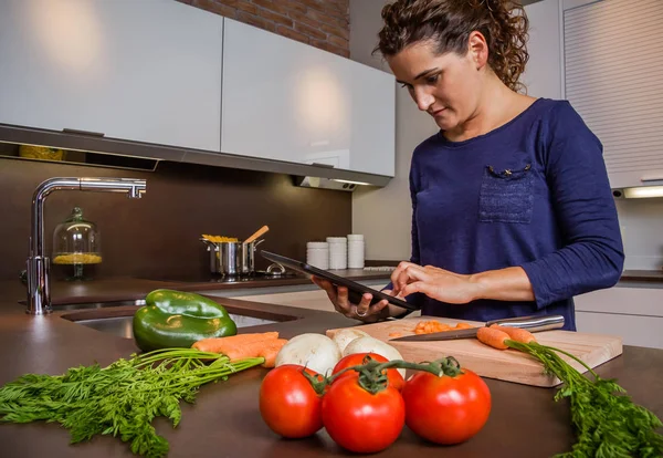 Meisje in huis keuken op zoek recept met een elektronische tablet — Stockfoto