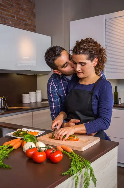 Couple hugging and preparing vegetables in the kitchen