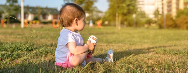 Boldog baba lány ül a fűben park játék — Stock Fotó