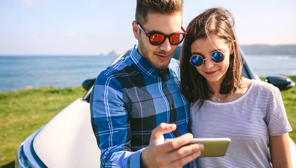 Couple with car looking mobile — Stock Photo, Image