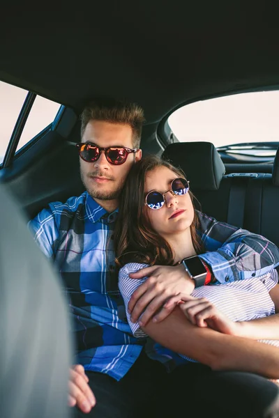 Young couple resting in the backseat of the car — Stock Photo, Image