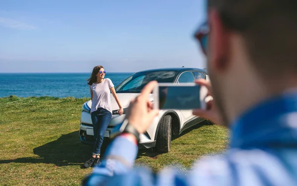Cara tirando foto de menina se apoiando em um carro — Fotografia de Stock