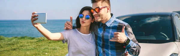 Young couple doing a selfie on the car — Stock Photo, Image